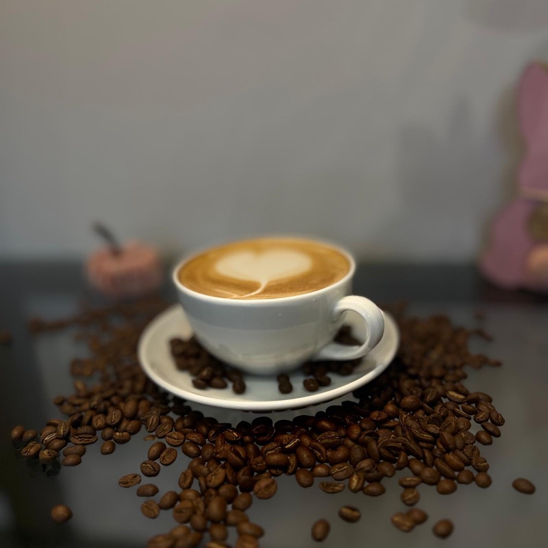 Cappuccino mit Herz-Latte-Art auf Kaffeebohnen
