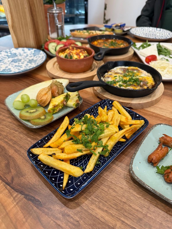 Deluxe Frühstück – reich gedeckter Frühstückstisch mit Pfannengerichten und frischem Obst