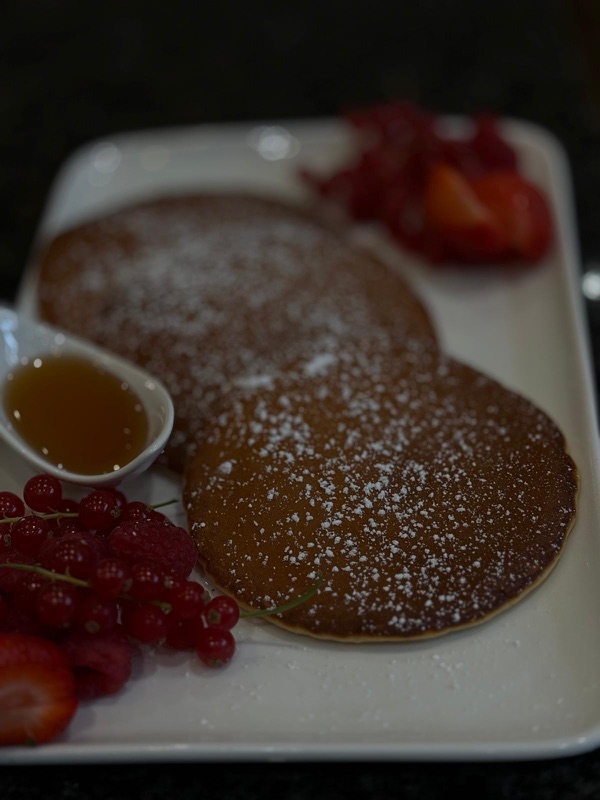Fluffige Pancakes mit Beeren, Ahornsirup und Puderzucker